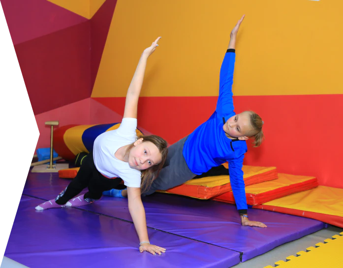 Мальчик и девочка из спортивной секции делают упражнение на одной руке на мате