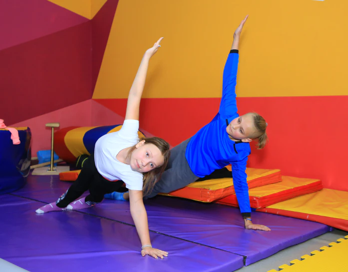 Мальчик и девочка из спортивной секции делают упражнение на одной руке на мате